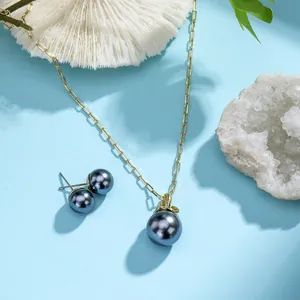 Detail of gold-plated necklace and grey shell pearl earrings on white coral stone