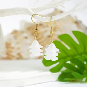 Detail of white resin floral earrings hanging on white coral with green leaves
