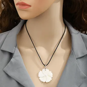 Colgante de flor de frangipani de concha natural en un collar de cordón negro minimalista