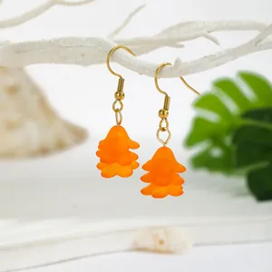 Detail of orange resin flower earrings with gold hooks on a bright natural background