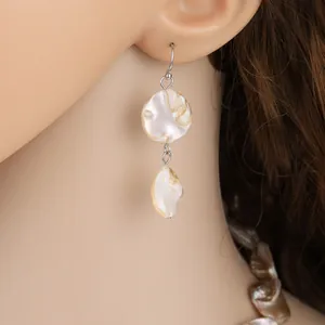 Detailed view of irregular natural shell drop earrings on model showcasing pearly luster