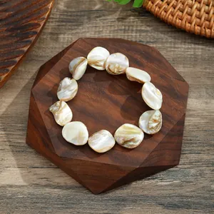 Close-up of a natural shell fragment bracelet on a hexagonal wooden display stand