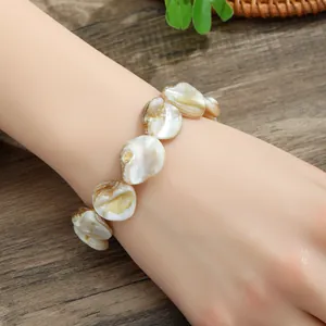 Irregular natural shell beaded bracelet with golden textures on a model's wrist