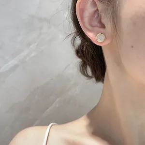 Close-up of bohemian gold-plated stud earrings with sea glass on a female model