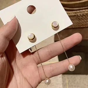 Detail of long gold chain earrings featuring white pearls and elegant shell inlay motifs