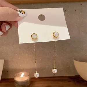 Detail of bohemian gold-plated dangle earrings with white pearls on a display card