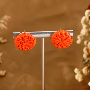 Handgefertigte runde Rattan-Ohrringe in hellem Orange auf einem Schmuckständer