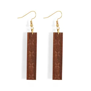 Dettaglio di orecchini in legno marrone con intricate incisioni floreali geometriche