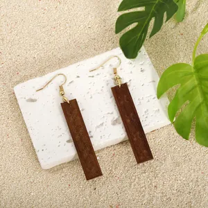 Dettaglio macro di orecchini rettangolari in legno marrone con intagli vintage