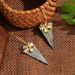 Makro-Detail von Boho-Ohrringen mit Muscheltextur und goldener Blume auf Holzgrund