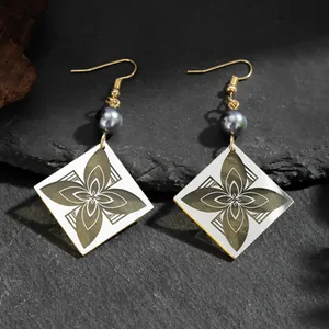 Pendientes vintage de acrílico con flores y ganchos dorados sobre fondo de piedra negra