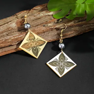 Detalle macro de pendientes cuadrados de acrílico con motivos florales y texturas retro