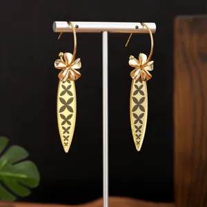 Detailansicht goldener Hängeohrringe mit Blumencharme und graviertem Anhänger
