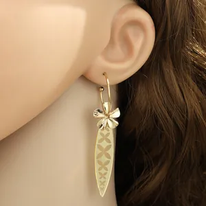 Nahaufnahme goldener langer Hängeohrringe mit Blumen- und Blattmotiven an einem Model