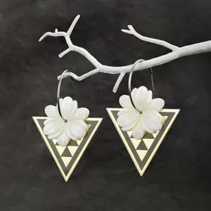 Detailaufnahme der Edelstahlohrringe mit geschnitzten Muschelblumen und Golddreiecken