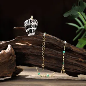 Vue macro du pendentif coquillage sur chaîne dorée avec perles vertes sur bois ancien