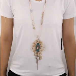 Elegant acrylic pearl necklace with vintage green pendant and metal tassel on white tee