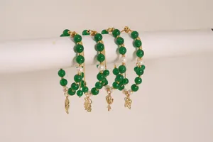 Detail of four-piece beaded bracelet set with green stones, pearls and gold charms
