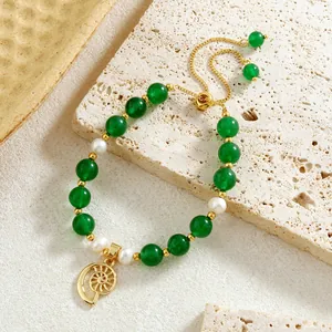 Detailed macro of green stone beads and white pearls bracelet with gold spiral charm