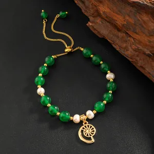 Detail of green agate and pearl beaded bracelet with sun charm and golden slide clasp