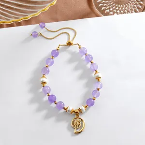 Détail d'un bracelet en améthyste et perles avec pendentif spirale doré et fermoir