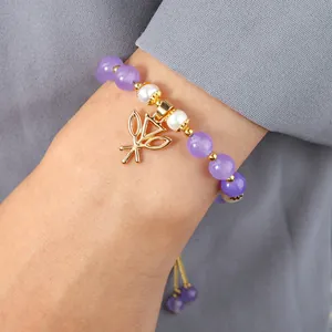 Détail du bracelet en améthyste et perles avec breloque feuille dorée au poignet