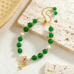 Detailed shot of green jade beads and pearls bracelet with gold floral charm