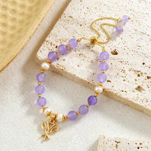Détail macro du bracelet fait main en améthyste et perles avec breloque feuille d'or