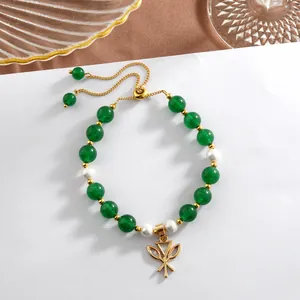Detail of green jade beads and natural pearl bracelet with a gold butterfly pendant