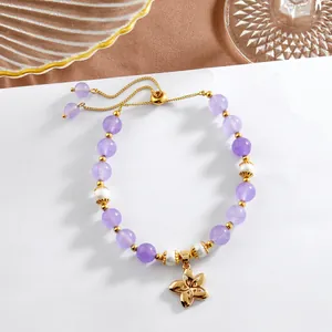 Détail du bracelet en améthyste et perles naturelles avec pendentif fleur dorée et chaîne réglable