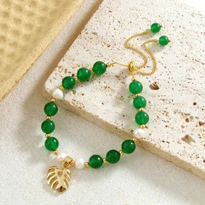 Detail of green jade and natural pearl bracelet with a golden monstera leaf charm