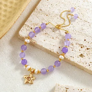 Détail du bracelet en améthyste et perles avec un charme de fleur plaqué or et perles