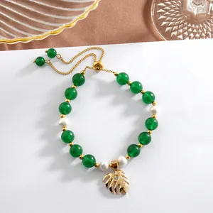 Detail of adjustable gold-plated chain bracelet with green jade beads and monstera charm