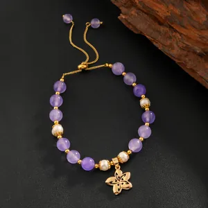 Vue détaillée du bracelet en améthyste et perles avec pendentif fleur en or