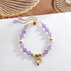 Détail d'un bracelet ajustable en améthyste et perles avec breloque cœur dauphin dorée