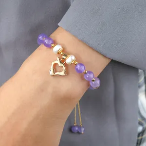 Détail macro du bracelet en améthyste et perles avec un pendentif en cœur doré