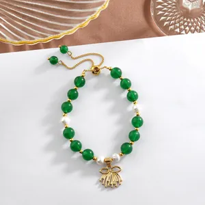 Detail of beaded bracelet with green jade beads, pearls and golden bow tassel charm
