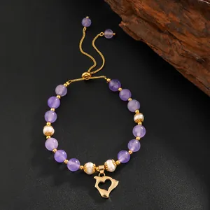 Gros plan d'un bracelet de perles d'améthyste et nacre avec un pendentif cœur doré