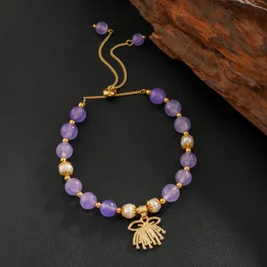 Détail d'un bracelet réglable en améthyste et perles avec breloque éventail dorée à l'or
