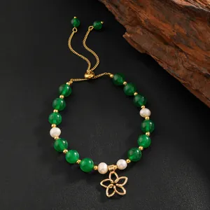 Vintage green jade and pearl beaded bracelet with a gold floral charm on black background