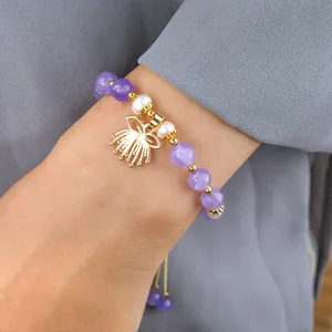 Détail d'un bracelet réglable en améthyste avec perles blanches et pendentif couronne dorée