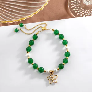 Close-up of beaded bracelet with green jade beads, pearls and a golden flower charm