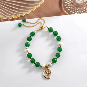 Detail of beaded bracelet featuring green jade beads, pearls, and a golden conch charm