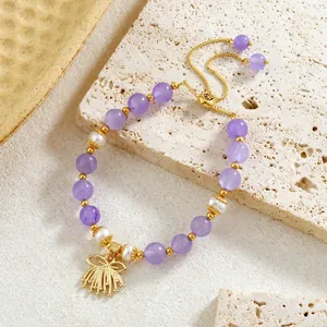 Gros plan de perles d'améthyste et perles naturelles avec pendentif nœud doré sur bracelet