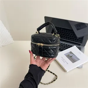 Quilted black mini handbag with gold chain and top handle in a minimalist setting