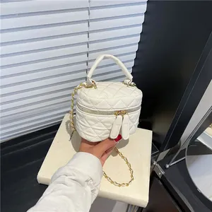 Chic beige quilted box bag with dual zippers and gold chain strap in a hand-held view