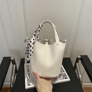 Sac seau en cuir grainé blanc avec foulard en soie décoratif sur une chaise