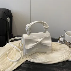 White bow-accented shoulder bag in premium matte PU leather with a twisted handle