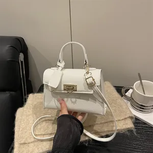 Elegante weiße Handtasche aus Leder mit Goldschloss und Schultergurt in Lifestyle-Szenerie