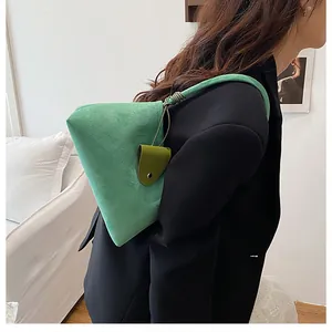 Detail of green suede shoulder bag with unique geometric shape and leather charm